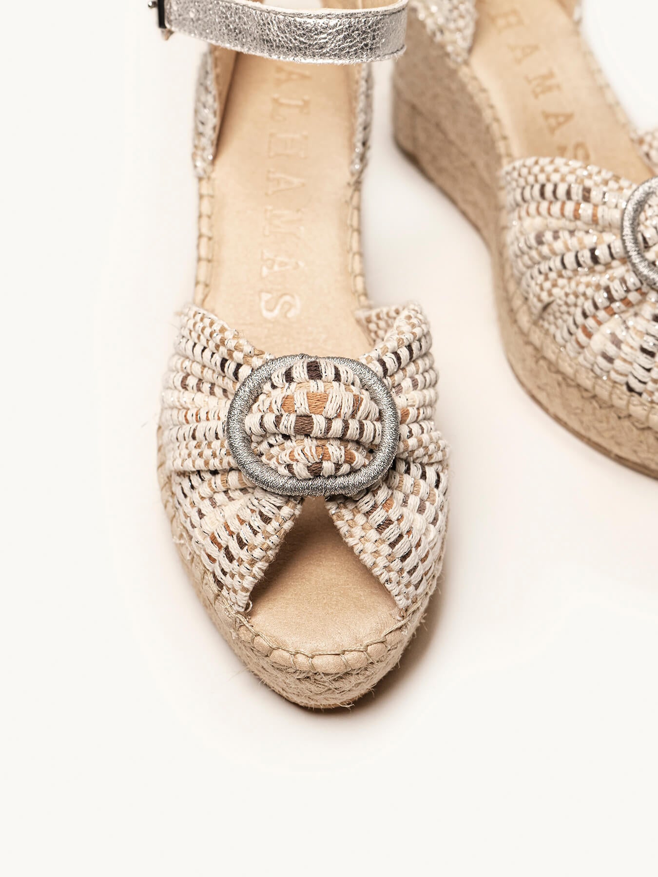 Pair of woven sandals with decorative buckle on a white background