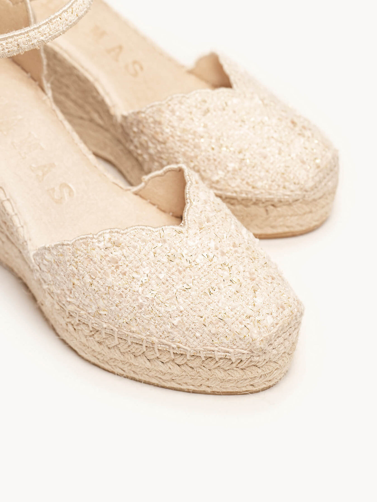 Pair of beige espadrille shoes on a white background