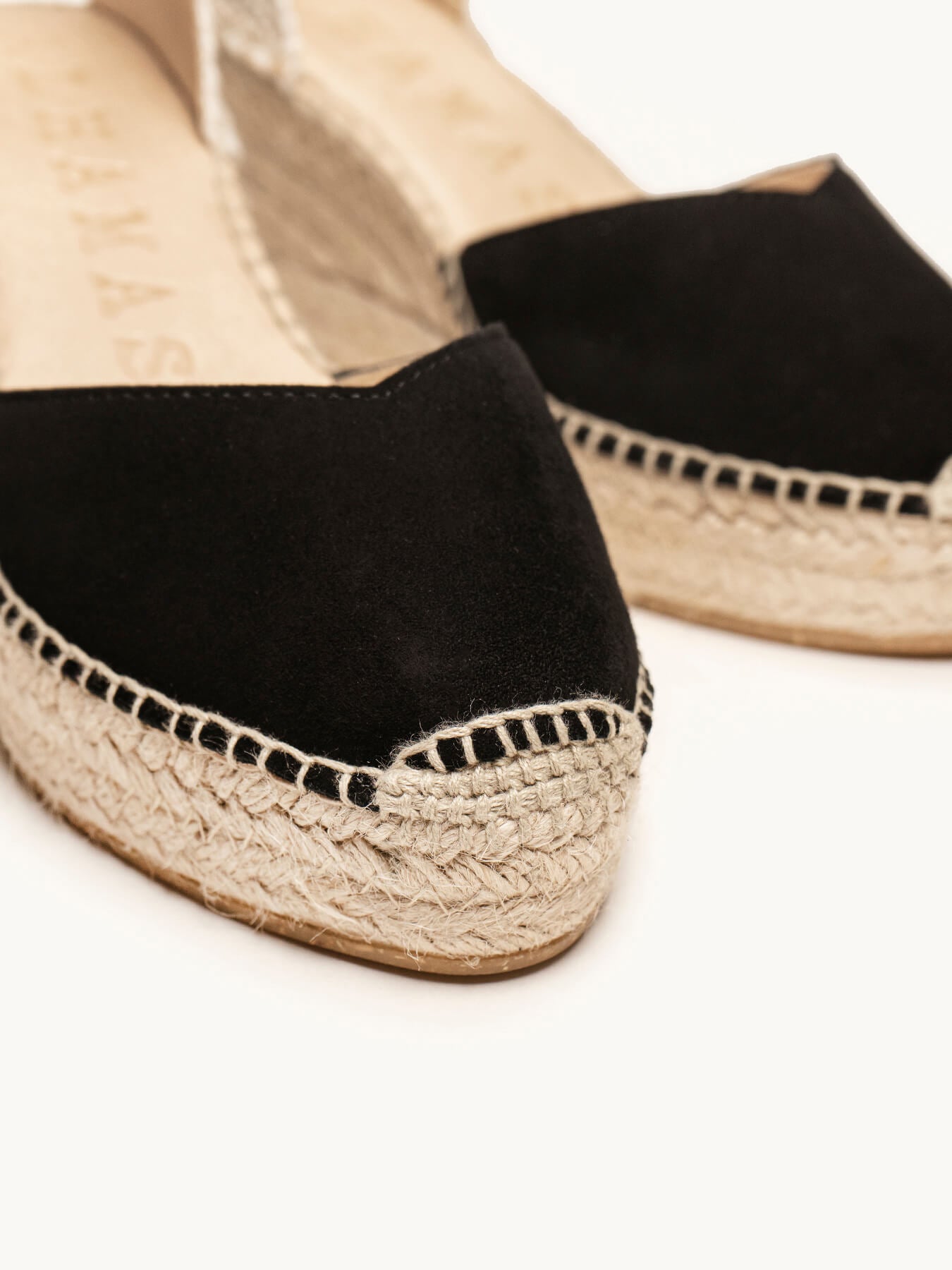 Black espadrille shoes with jute sole on a white background