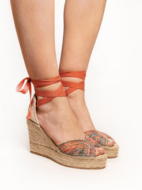 Orange wedge sandals with espadrille sole on a white background