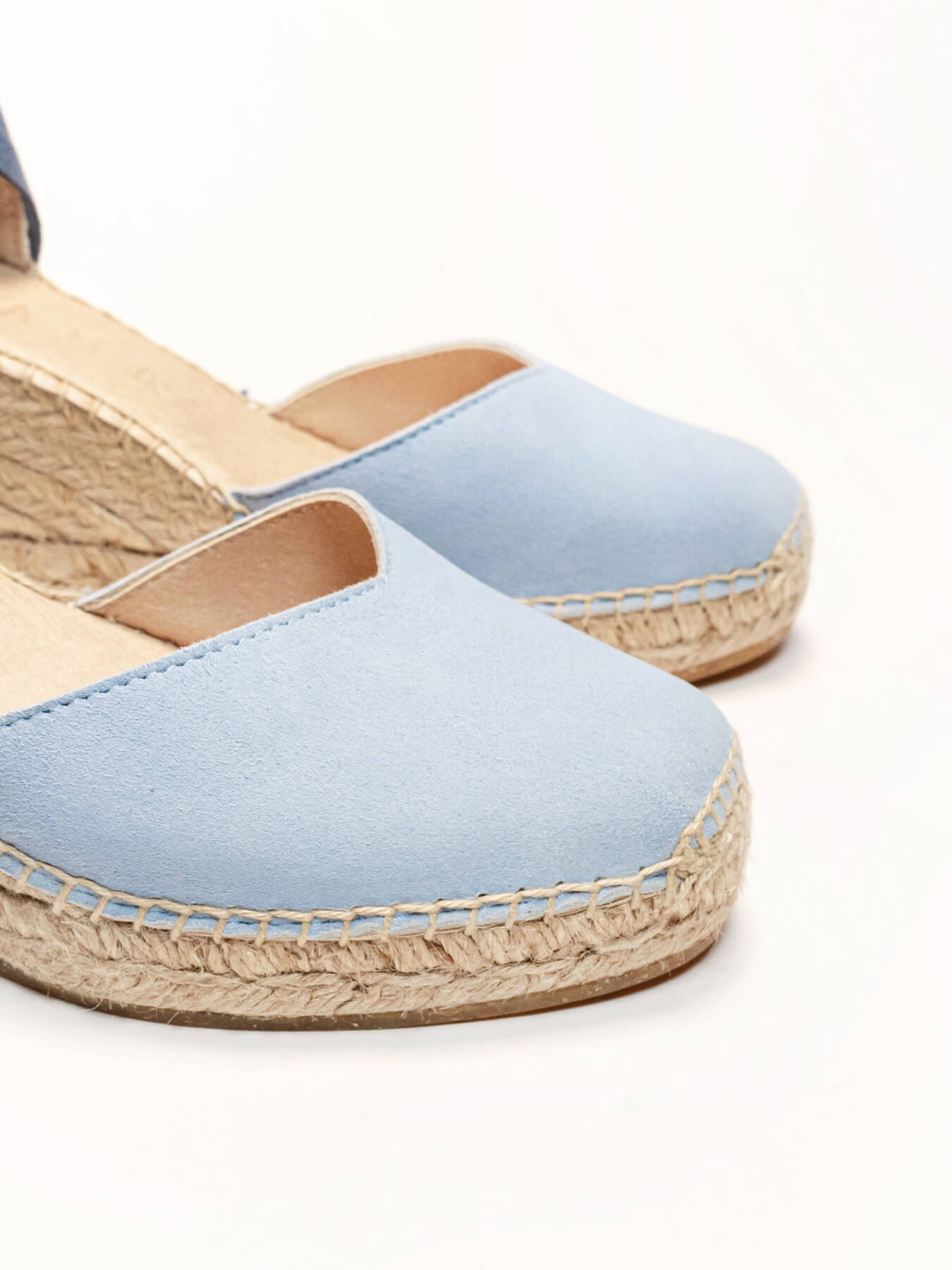 Pair of light blue espadrille sandals on a white background