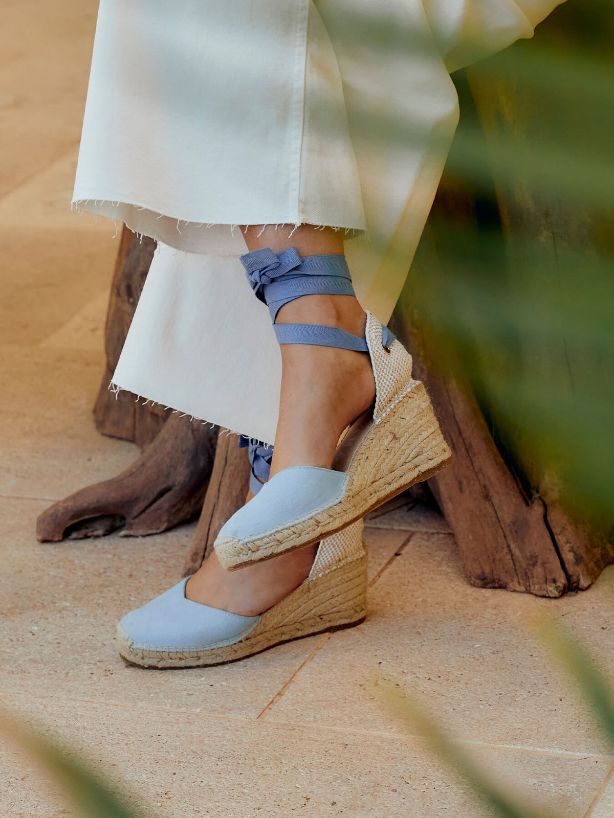 Person wearing light blue wedge sandals with a textured sole