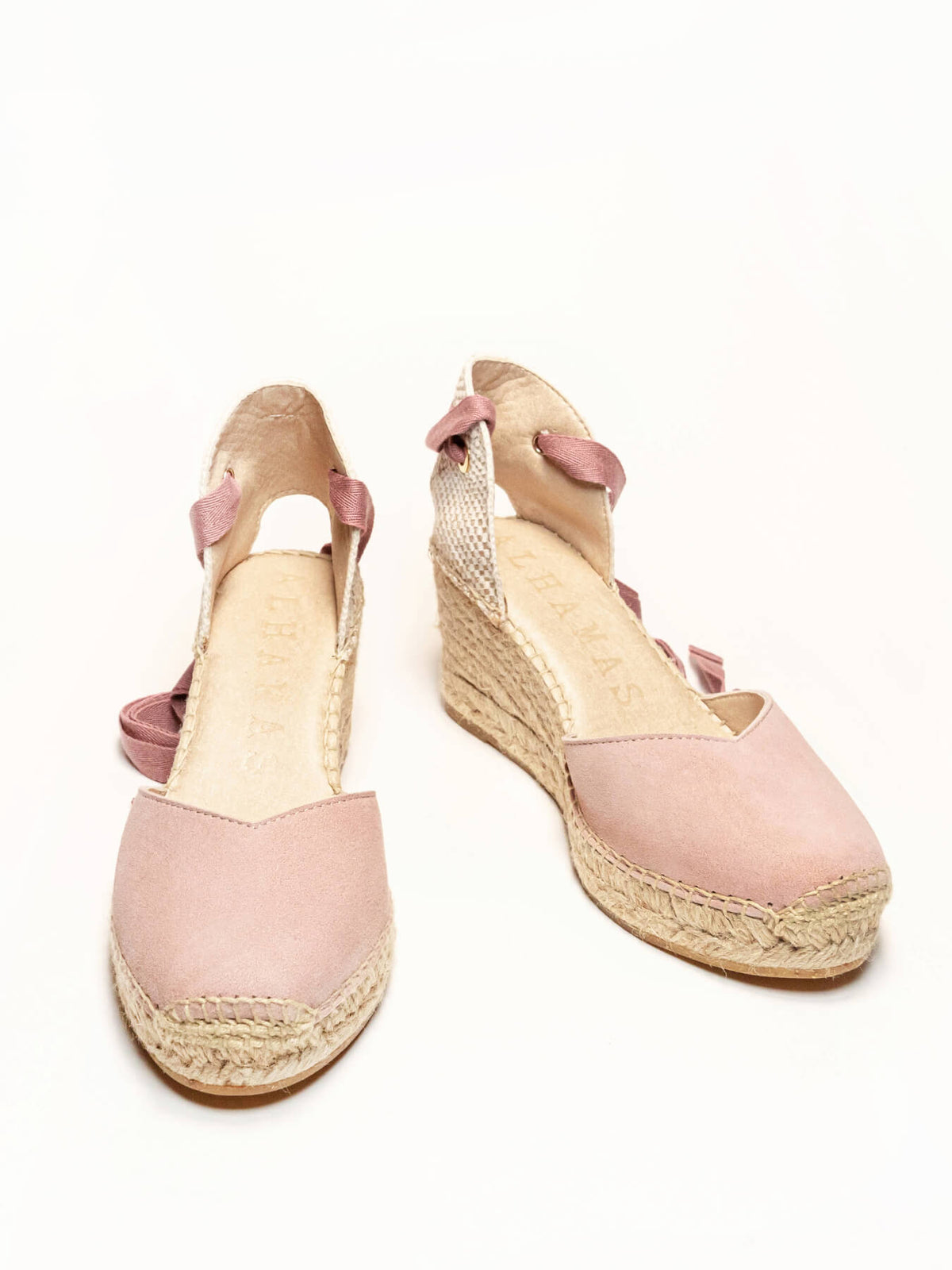 Pair of pink wedge sandals with espadrille soles on a white background