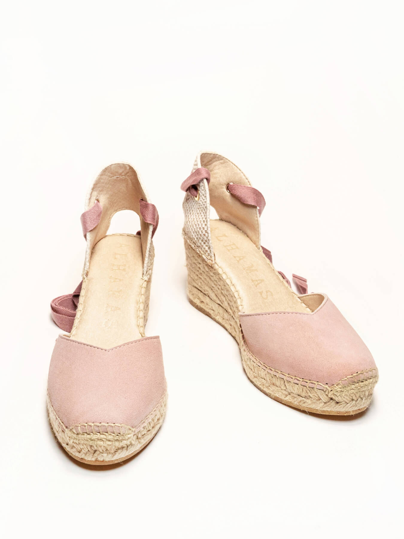 Pair of pink wedge sandals with espadrille soles on a white background
