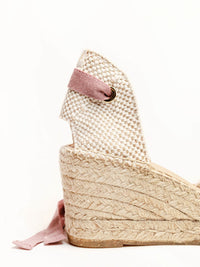 Woven wedge sandal with pink strap on a white background